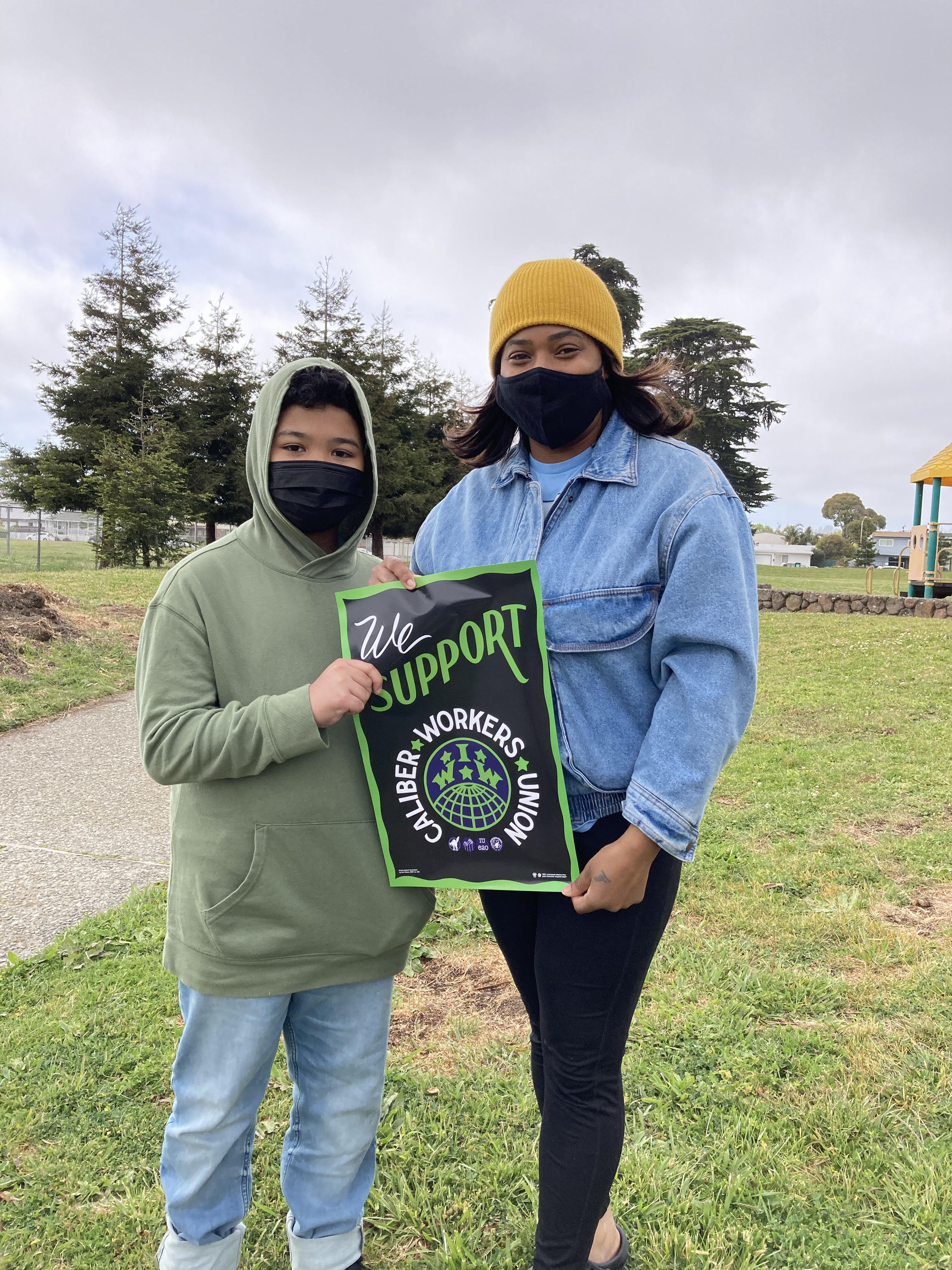 Two Caliber Workers Union members holding a sign in support of teachers and their union.