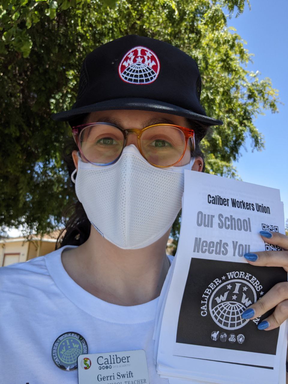 Caliber teacher and Caliber Workers Union member wearing a union button and holding a a stack of pro-union fliers.